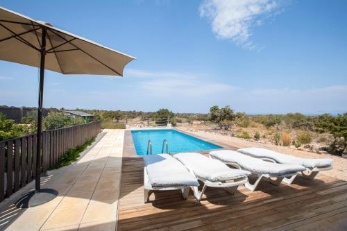 a row of white lounge chairs next to a swimming pool at VILLA Can Guillem d'es Puig in Sant Francesc Xavier