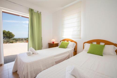 two beds in a bedroom with a view of the beach at VILLA Can Guillem d'es Puig in Sant Francesc Xavier