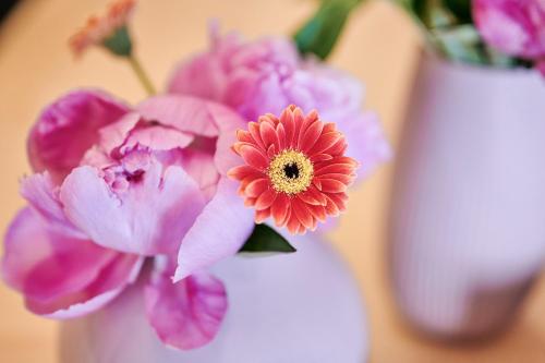 a white vase with pink flowers in it at Omesberg-Hütt'n in Lech am Arlberg