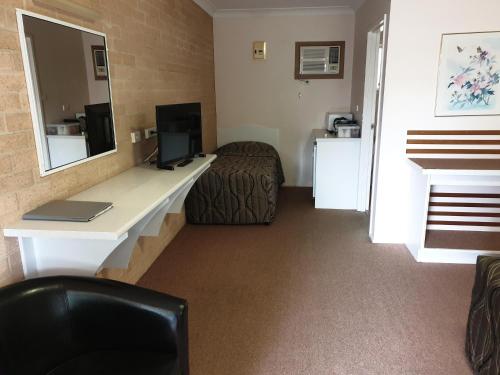 a hotel room with a desk and a bed at Blayney Central Motel in Blayney