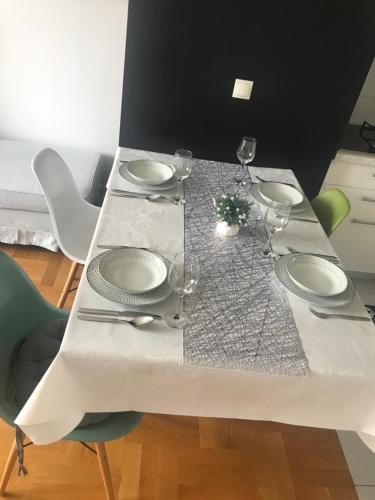 a white table with plates and wine glasses on it at Luna Apartments, apartments with style in Zagreb