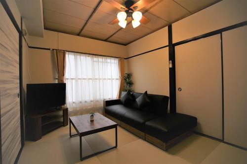 a living room with a black couch and a table at Fukuoka Condominium in Fukuoka