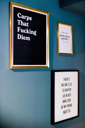 a chalkboard sign on a blue wall with two pictures at Boutiquehotel Caravella Velden by S4Y in Velden am Wörthersee