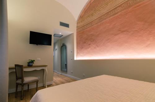 a room with a bed and a desk and a television at Il giardino di Pantaneto Residenza D'Epoca in Siena
