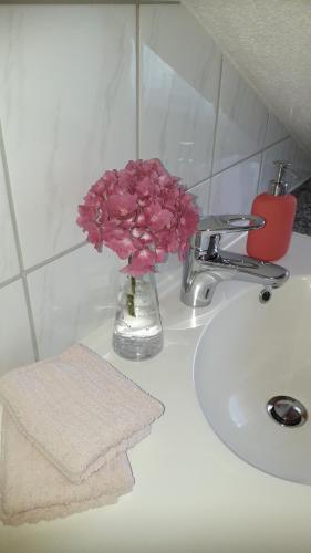 a vase of pink flowers sitting on a bathroom sink at Gästehaus Alpenblick in Mutters