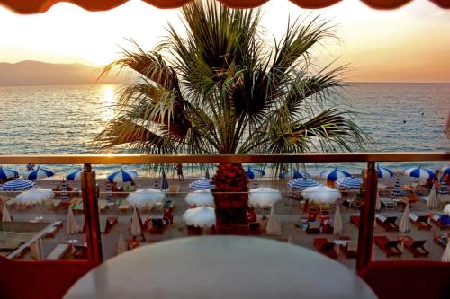 a view of a beach with chairs and a palm tree at Palmanova Beach Mardok in Vlorë