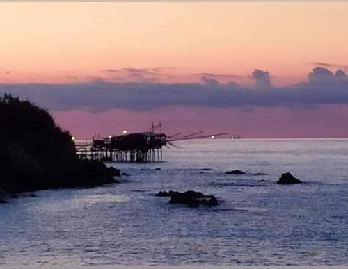 a pier in the water with a sunset in the background at Dannunziano Aparthotel in Chieti