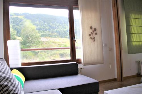 uma sala de estar com um sofá e uma grande janela em ÁLIGA CONFORT Vistas a pie de pistas em El Tarter