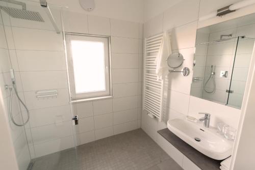 une salle de bain blanche avec un lavabo et une douche dans l'établissement Ostseehaus am Naturstrand - Ostseeblick, à Varnkevitz