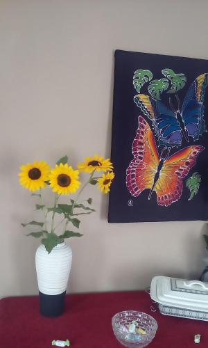 a vase of flowers on a table with a butterfly painting at La Vatura in Gialova