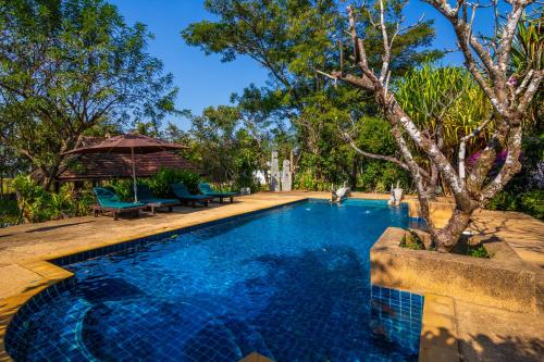una piscina con sillas, sombrilla y árboles en Jasmine Hills Lodge, en Doi Saket