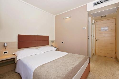 a bedroom with a large bed with a wooden headboard at Hotel Mediteran Plava Laguna in Poreč