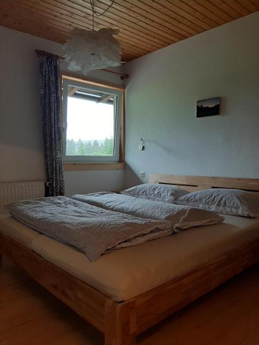 a large bed in a bedroom with a window at Gästehaus Koch in Zöblen