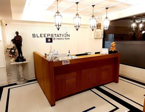 a hotel reception desk with a statue of a man at Sleepstation at Pratunam in Bangkok
