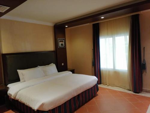 a large bed in a hotel room with a window at Durrah Beach Apartment in Durat Alarous