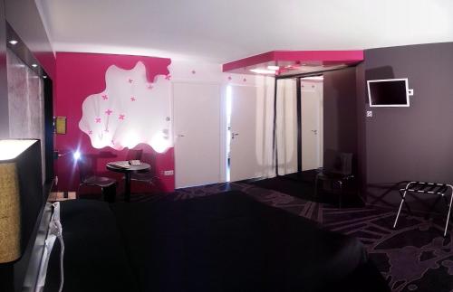 a room with a pink wall with a table and chairs at Le Ceïtya in Saint-Gilles-Croix-de-Vie