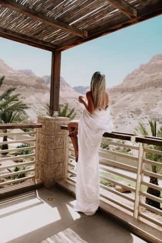 a woman standing on a balcony looking out at the desert at Ein Gedi Kibbutz Hotel in Ein Gedi