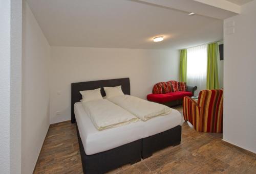 a bedroom with a bed and a red chair at Landgasthof Werdenberg in Werdenberg