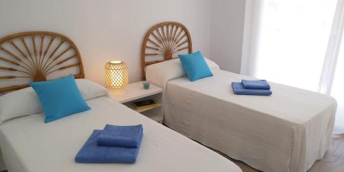 - 2 lits dans une chambre avec des oreillers bleus dans l'établissement SCALA Apartaments, à Salou