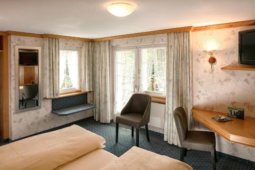 a hotel room with a bed and a desk and window at Hotel Alpenblick in Weissbad