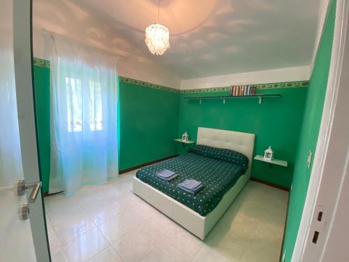 ein grünes Schlafzimmer mit einem Bett mit einer grünen Wand in der Unterkunft Casa Vacanze Gli Allori in Venarotta