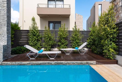 a swimming pool with two lounge chairs next to a house at Ixia Breeze 2 in Ixia