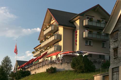 a hotel building with tables and chairs and a flag at Hotel Alpenblick in Weissbad