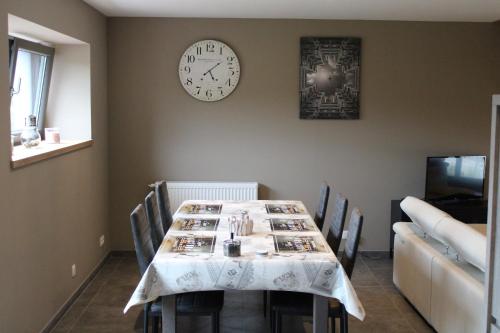 a dining room with a table and a clock on the wall at L’Ancienne Grange 1916 in Chevetogne