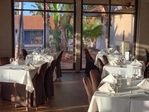 a restaurant with white tables and chairs and large windows at Hospitality Port Hedland in Port Hedland