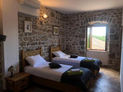 Habitación con 2 camas y paredes de piedra. en Bed&Breakfast Agroturizam Antunović, en Kuna Pelješka