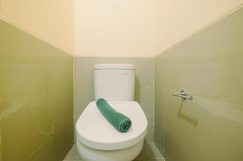a bathroom with a toilet with a green hose at Studio Kebayoran Icon Apartment near Gandaria City Mall By Travelio in Jakarta