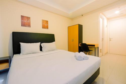 a bedroom with a large white bed with shoes on it at Studio Kebayoran Icon Apartment near Gandaria City Mall By Travelio in Jakarta