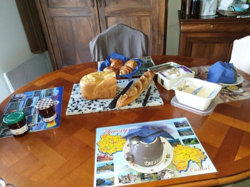 a table with bread and croissants and a tea pot at Brigitte Carbonnel in Aydat