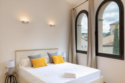 a bedroom with a white bed with two windows at Flateli Sant Fèlix in Girona