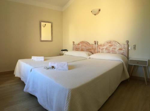 two beds in a hotel room with white sheets at Apartamentos Surest in Cala en Blanes