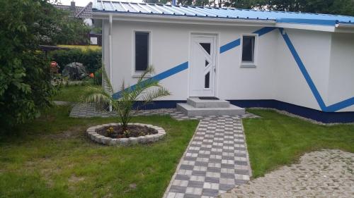 ein kleines weißes Haus mit einer Tür im Hof in der Unterkunft Ferienhaus „Strandhafer“ in Zingst