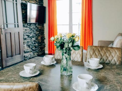 a vase of flowers sitting on a table with two cups at Kaszubskie Zacisze in Władysławowo
