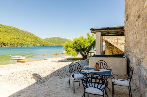 uma mesa e cadeiras numa praia com a água em Holiday Home Barbara em Ston