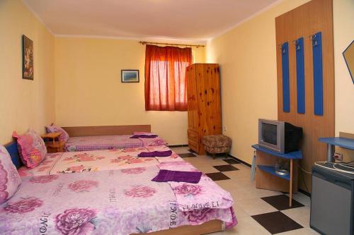 a bedroom with two beds and a television at Семеен хотел Бостън in Ravda