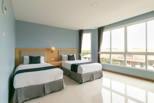 two beds in a room with large windows at Golden Beach Boutique Resort in Prachuap Khiri Khan