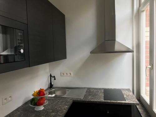 a kitchen with black cabinets and a bowl of fruit on the counter at Brussel House Basilic in Brussels