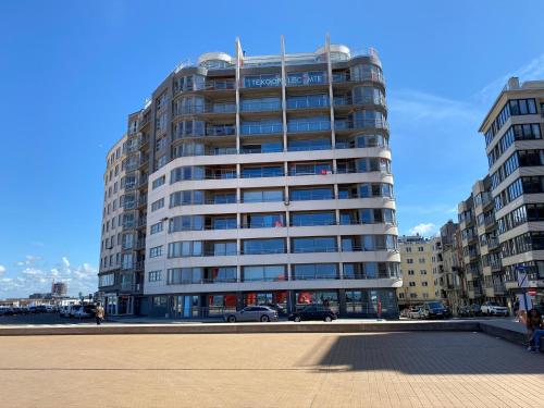 a tall building with cars parked in front of it at Panoramic view on beach, ships, sea - place to be in Ostend