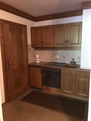 a kitchen with wooden cabinets and a black stove top oven at Pension Millinger in Sankt Martin bei Lofer