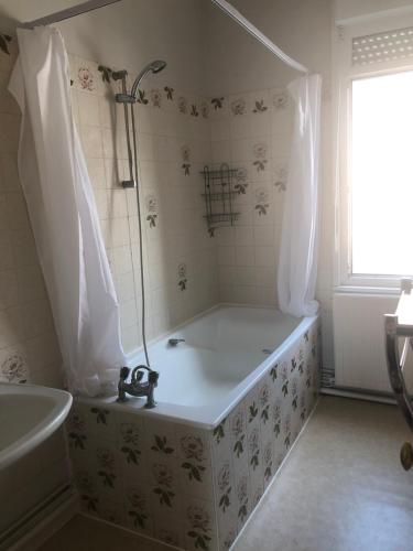 ein weißes Bad mit einer Badewanne und einer Dusche in der Unterkunft Spacious Quentoinise Town House in Saint-Quentin