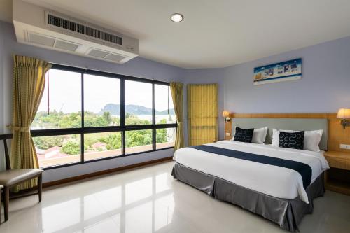 een slaapkamer met een groot bed en een groot raam bij Golden Beach Boutique Resort in Prachuap Khiri Khan