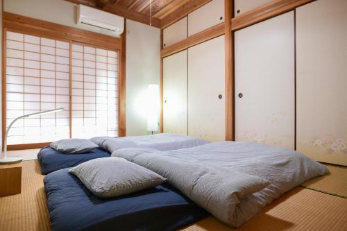 two beds in a room with windows at South Coast house in Yakushima
