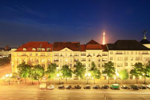 a large white building with cars parked in a parking lot at Hotel Brandies Berlin GmbH in Berlin