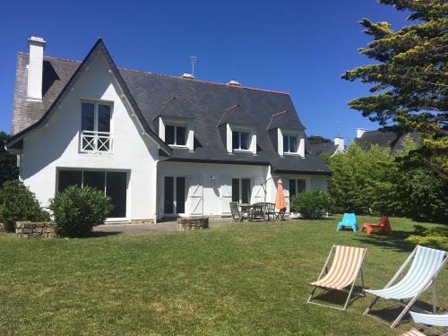 a white house with two lawn chairs in the yard at Holiday Home Maison Courlis by Interhome in Carnac