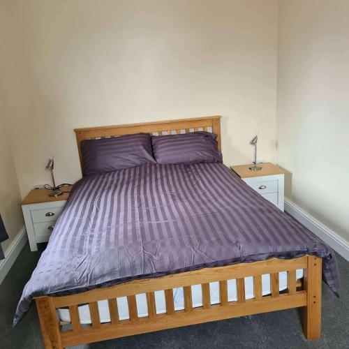 a bedroom with a wooden bed with a purple comforter at 3 Wood Yard Cottages, Red Mayes Farm in Long Sutton