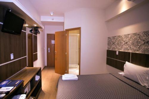 a bedroom with a bed and a television and a door at Druds Hotel Hortolândia in Hortolândia